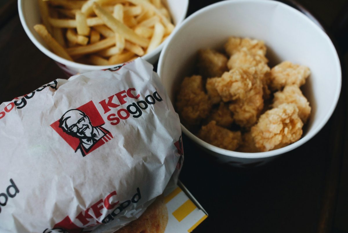 Burger KFC, kura a hranolky v bielych miskách pripravené na servírovanie. Rýchly fast-food obed.