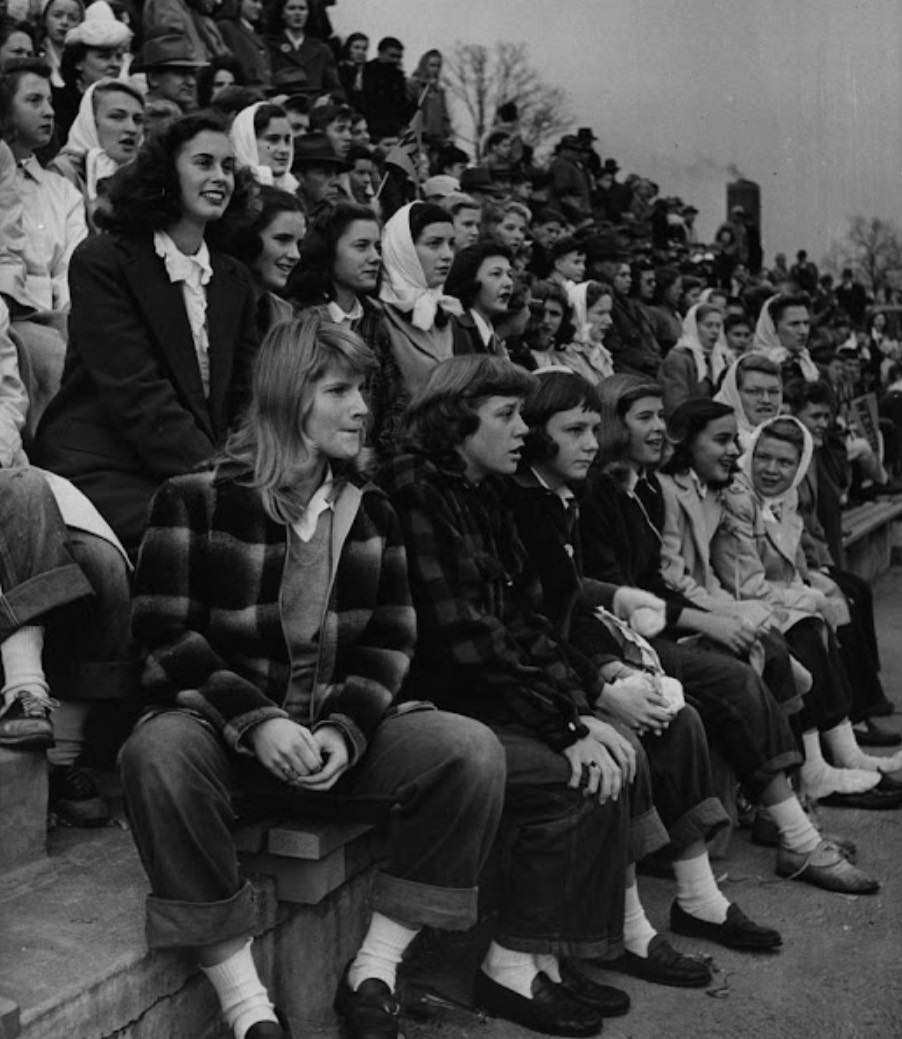 Skupina divákov sleduje športové podujatie na tribúne, 50. roky, čierno-biela fotografia.