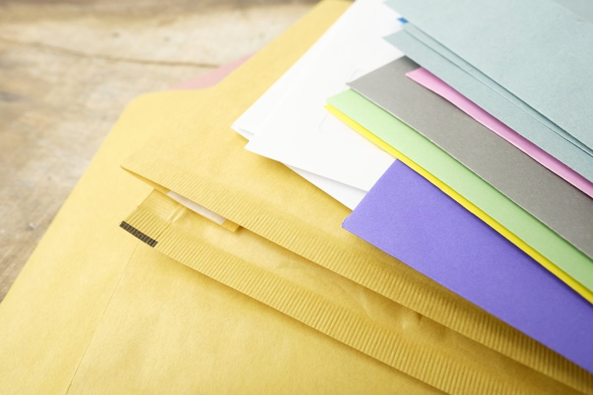 Farebné obálky a papier na drevenom stole, vhodné na organizáciu dokumentov.
