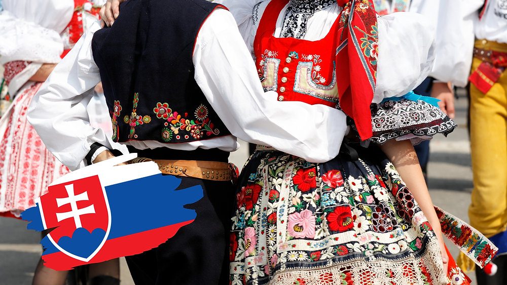 Slovenské ľudové kroje v tradičnom tanci, detail farebnej výšivky a slovenská vlajka.