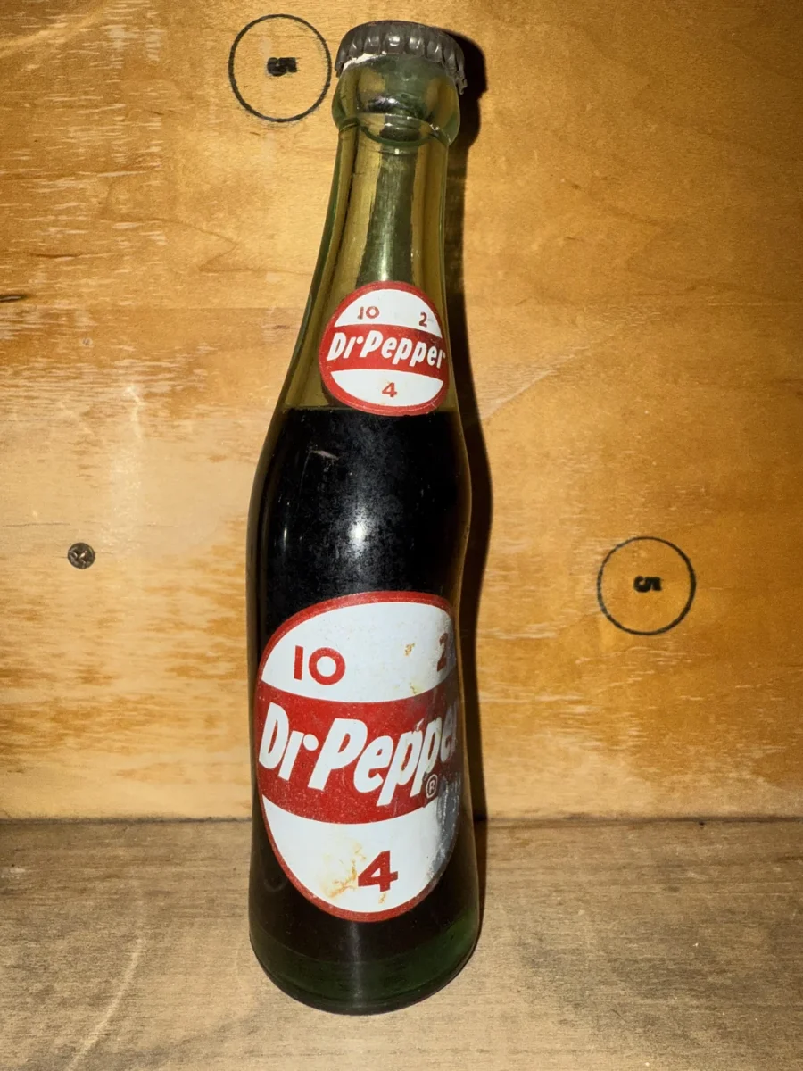 Starodávna fľaša Dr Pepper na drevenom pozadí, ukazujúca retro dizajn etikety.