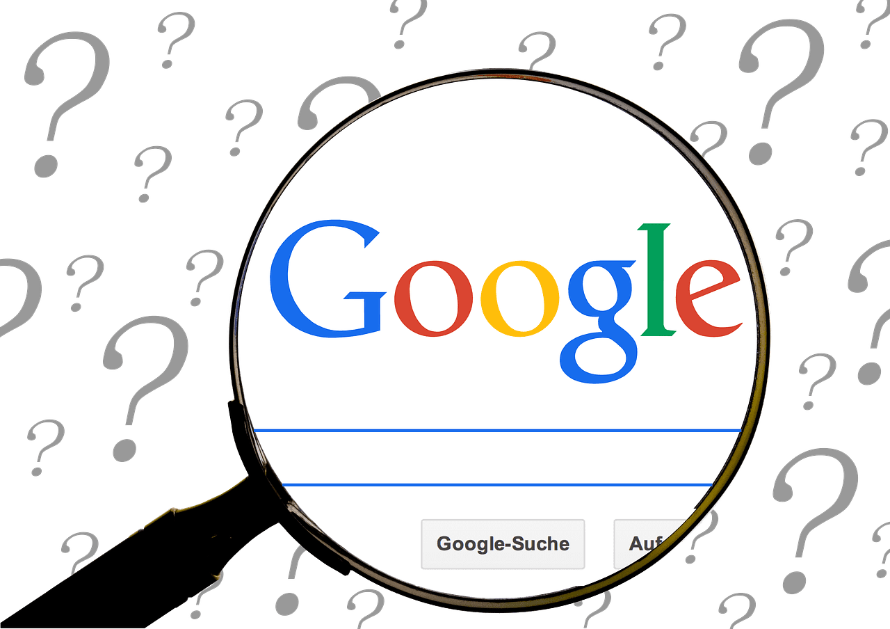 Lupa zvýrazňuje vyhľadávač Google obklopený otáznikmi, symbolizujúci hľadanie odpovedí online.