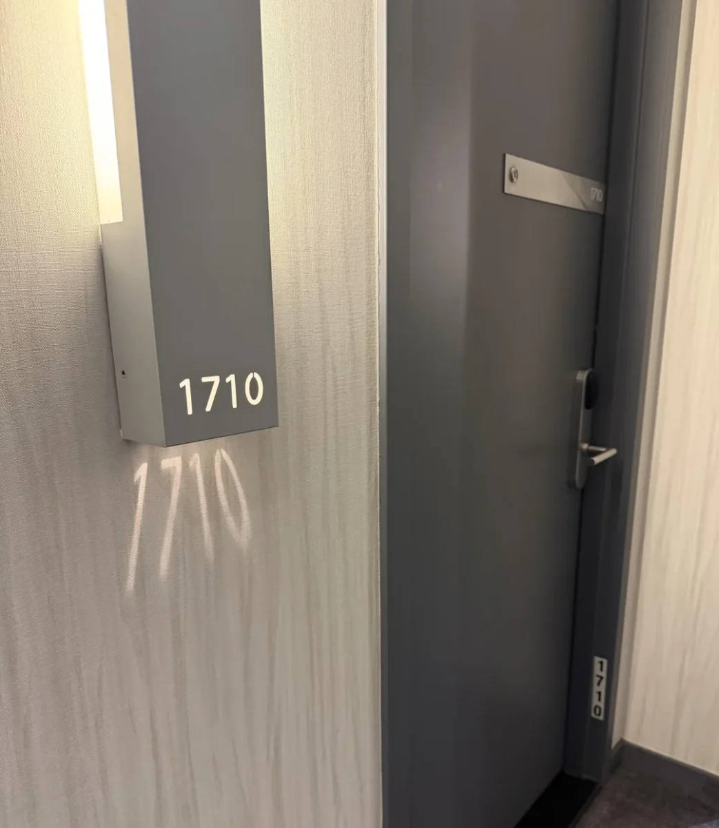 Dvere hotelovej izby s označením 1710 a tieňom čísla na stene.