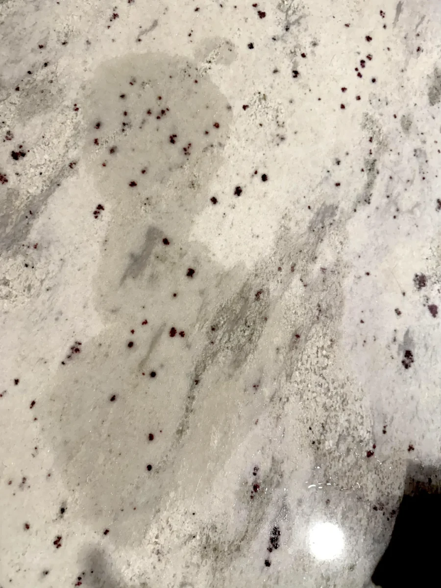 Detailný záber na mramorovú dosku s tmavšími škvrnami na svetlom podklade.