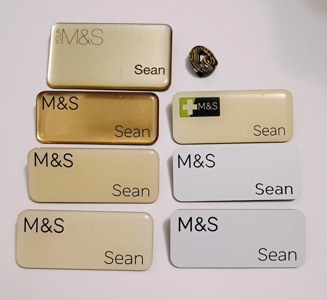 Rôzne odznaky M&S s menom Sean na bielom pozadí, vrátane vyznamenania za desaťročie služby.