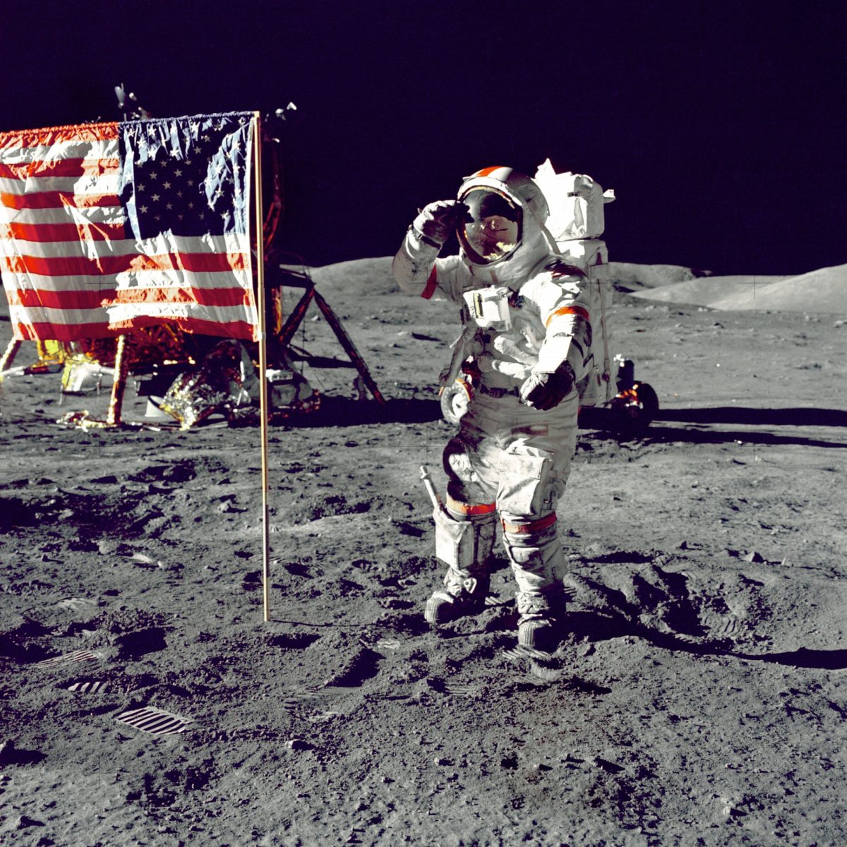 Astronaut na Mesiaci pri vlajke USA, s lunárnym modulom v pozadí, salutuje.