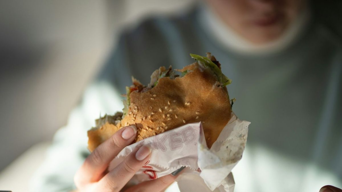 Osoba drží chutné polovypité kebab v rukách, pripravené na zahryznutie.