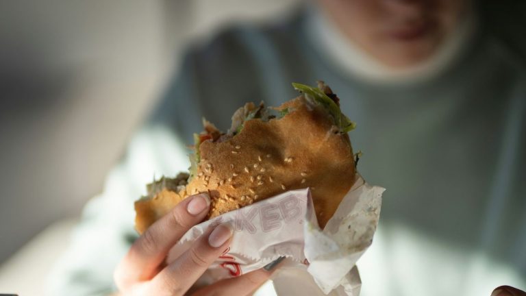 Osoba drží chutné polovypité kebab v rukách, pripravené na zahryznutie.