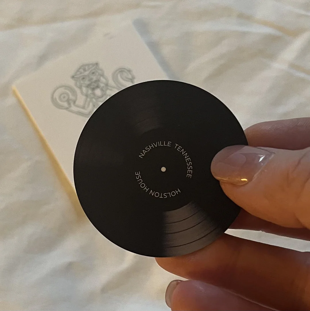 Malá vinylová platňa s nápisom Nashville Tennessee držená v ruke, rozmazané pozadie.
