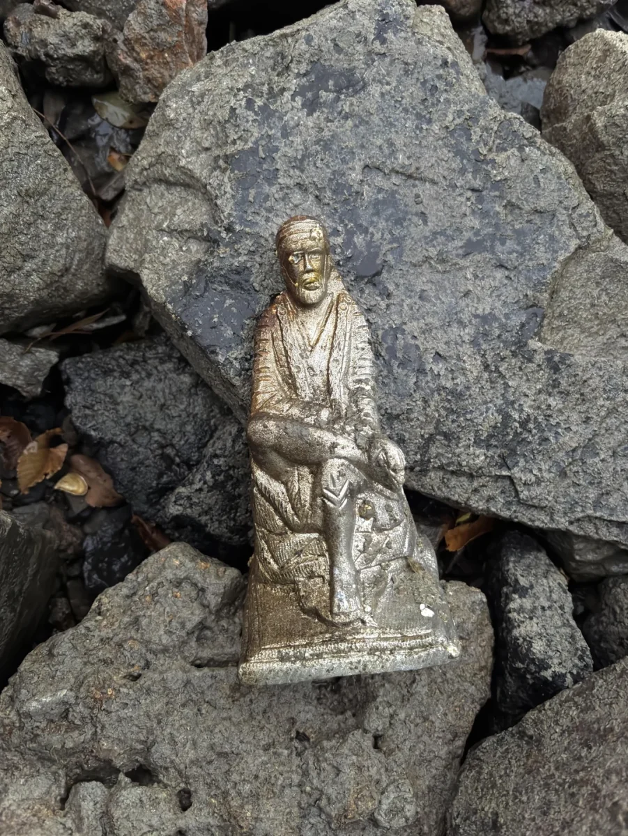 Zlatá soška na pozadí kamenia: umelecký výtvor s detailami, kontrastujúci s prírodnou textúrou skál.