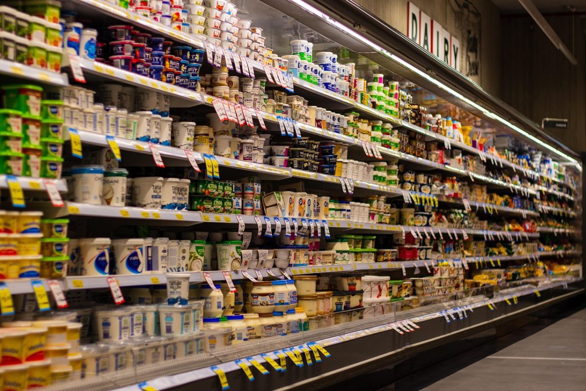 Regály plné mliečnych výrobkov v supermarkete: jogurty, syry, smotana, ponuka produktov.