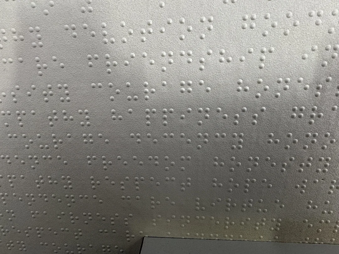 Písmo Braille na šedej textílii - detailná textúra hmatového písma pre nevidiacich.