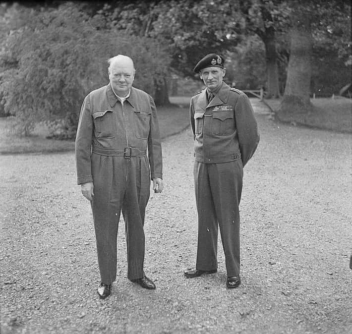 Dvaja muži v vojenských uniformách stoja spoločne na štrkovej ceste v parku.