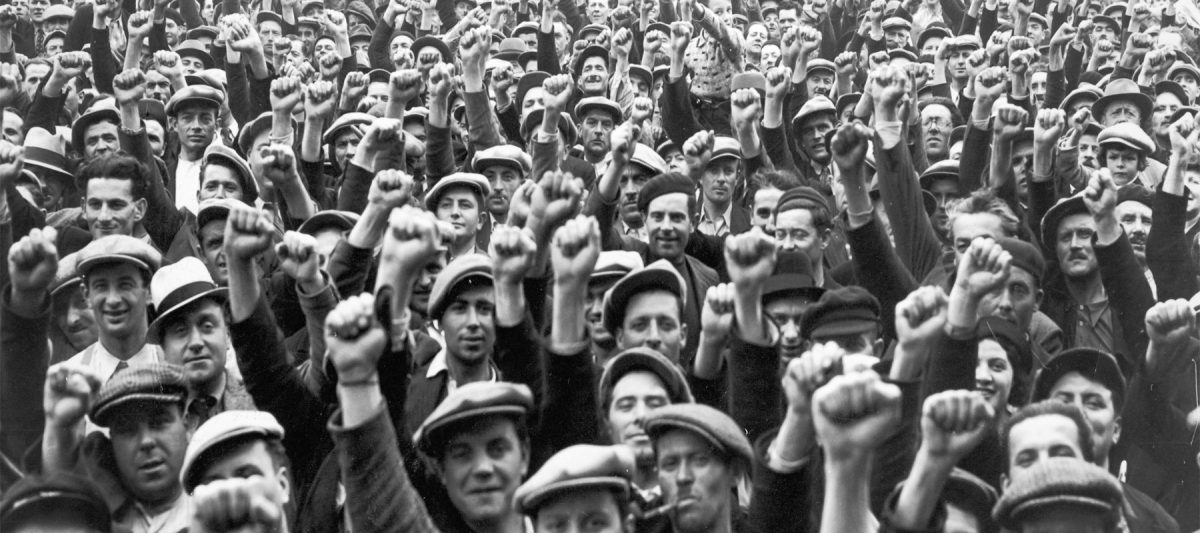 Skupina ľudí zdvíhajúcich päste, prejav solidarity a jednoty na verejnom zhromaždení.