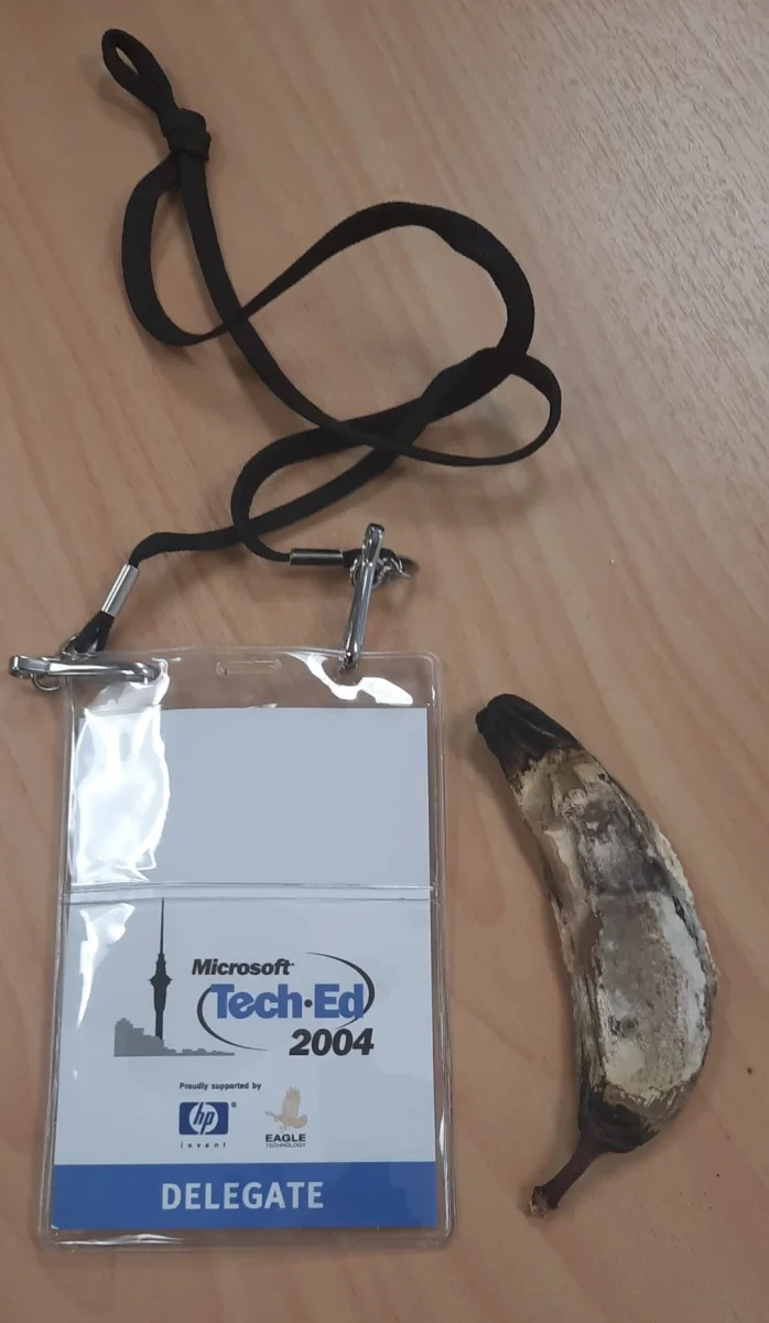 Identifikačný preukaz Microsoft Tech-Ed 2004 s vysušeným banánom na drevenom stole.