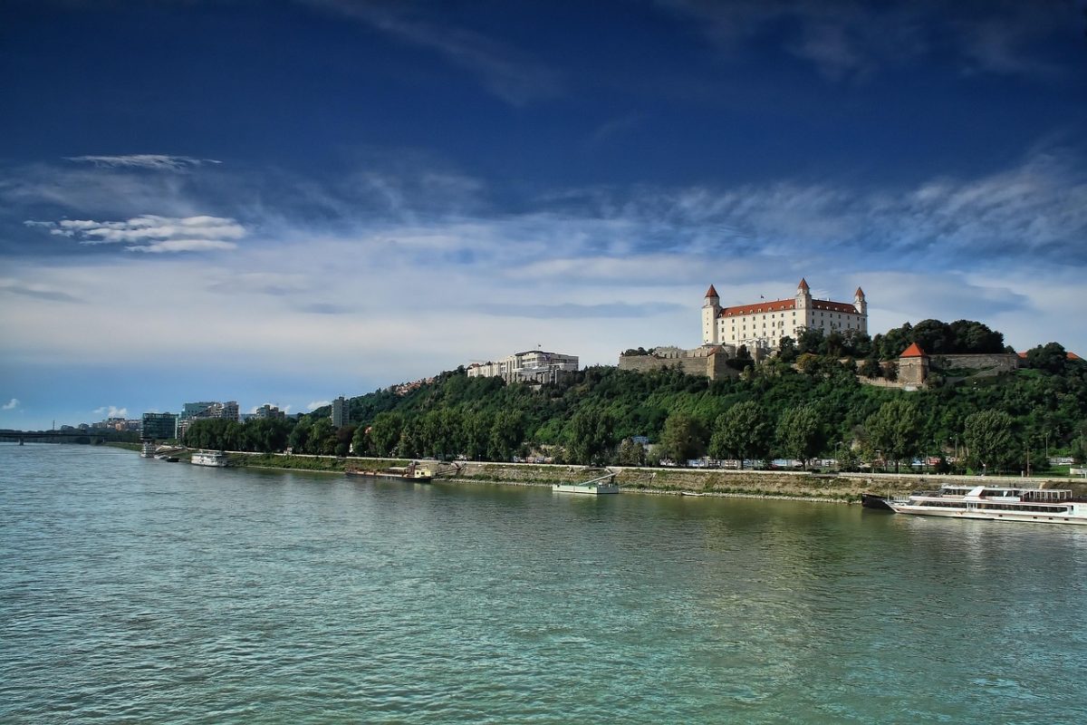 Pohľad na Bratislavský hrad a rieku Dunaj pod modrou oblohou. Úchvatná scenéria mesta Bratislava cez deň.
