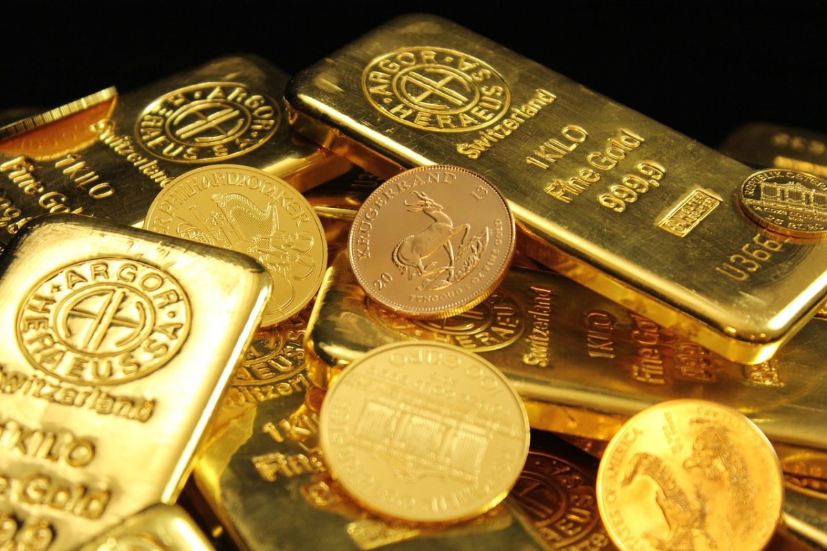 Zlaté tehličky a mince, symboly bohatstva a investícií, ležiace na sebe v svetle lesku zlata.