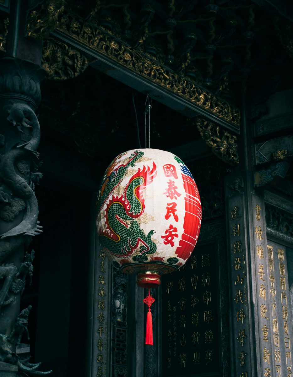 Tradičná čínska papierová lampa s drakom a kaligrafiou visí v zdobenom chráme.