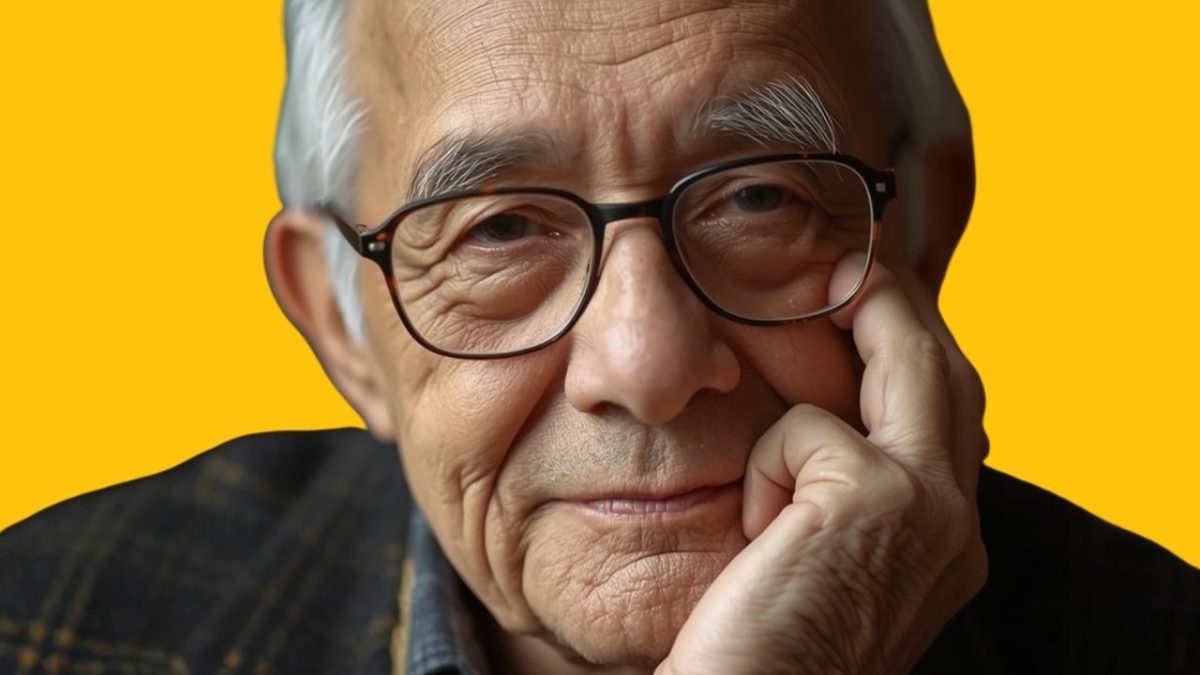 Senior s okuliarmi na žlto-oranžovom pozadí, zamyslene oprie hlavu o ruku.