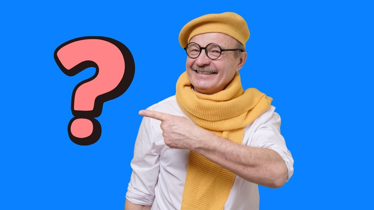 Starší muž v žltom baretku s úsmevom ukazuje na ružový otáznik na modrom pozadí.