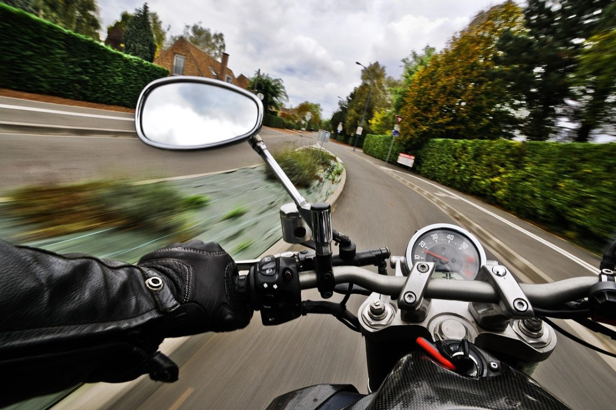 Motorkár jazdiaci zákrutou so zameraním na rýchlomer a riadidlá motocykla.