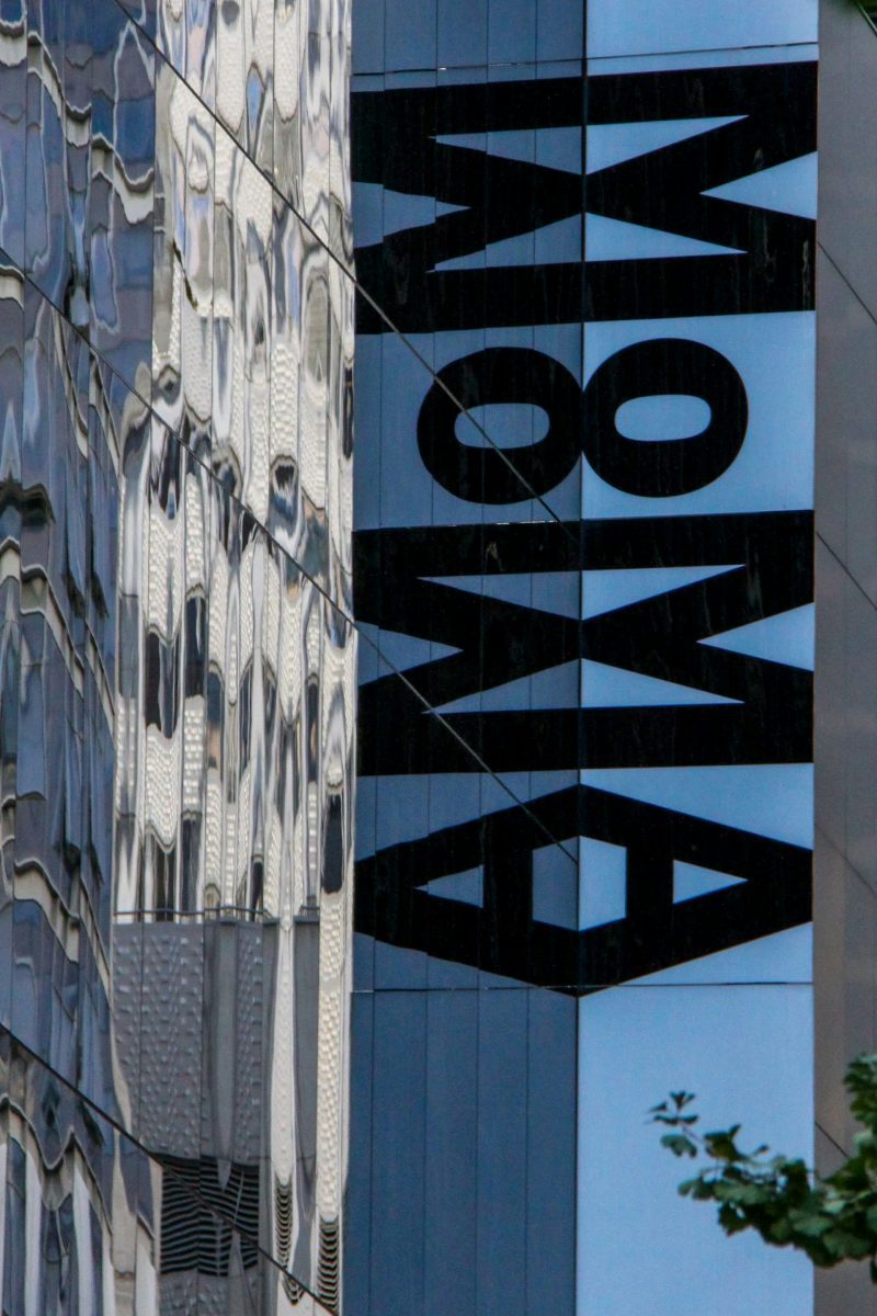 Moderná budova s efektom zrkadlového odrazu a nápisom. Minimalistická architektúra v mestskom prostredí.