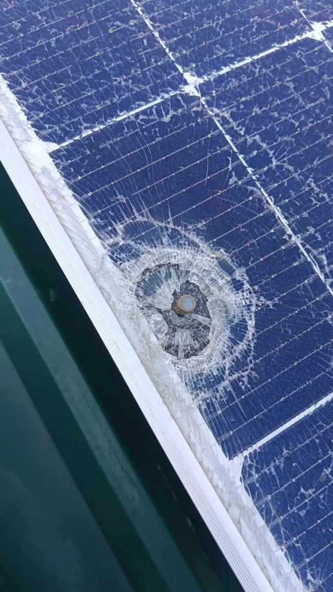 Poškodený solárny panel s výrazným prasknutím okolo stredu, poškodenie skla v dôsledku nárazu.