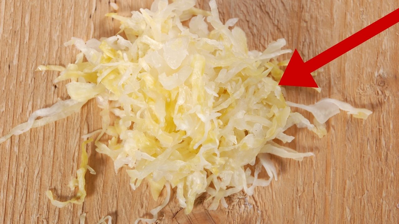 Nakrájaná kvasená kapusta na drevenej doske s červenou šípkou poukazujúcou na kapustu.