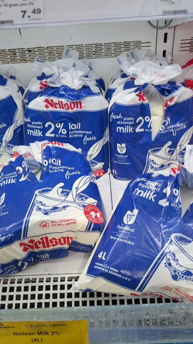 Balenie 2% mlieka Neilson v sáčkoch na poličke, čerstvé čiastočne odstredené, 4 litre, modro-biely obal.