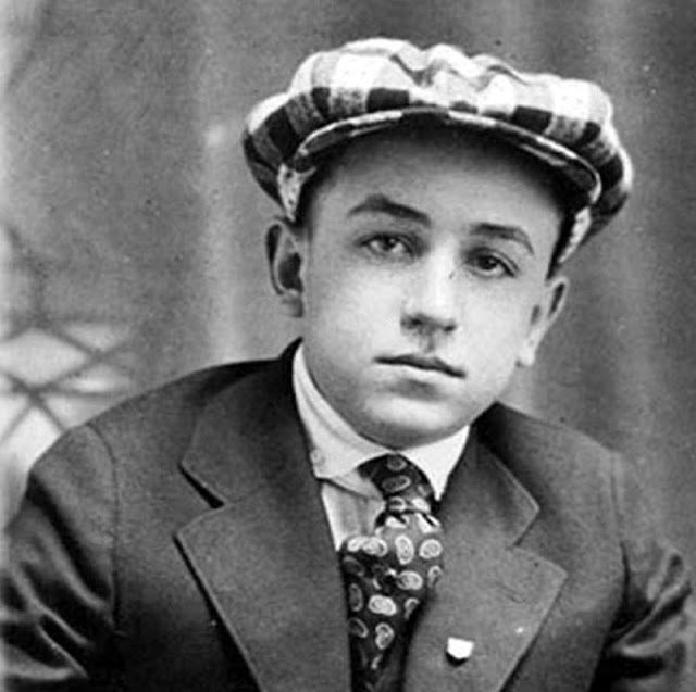 Neznámy mladík v obleku a klobúku, historická čiernobiela fotografia.