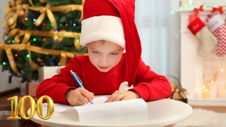 Chlapec v mikine so santovskou čiapkou píše list na Vianoce pri ozdobenom stromčeku.