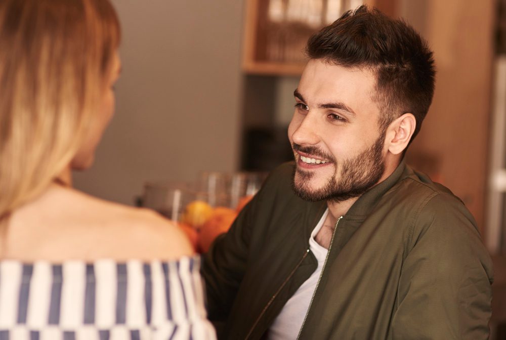 Muž sa usmieva pri rozhovore s ženou v kaviarni. Elegantná a príjemná atmosféra stretnutia.