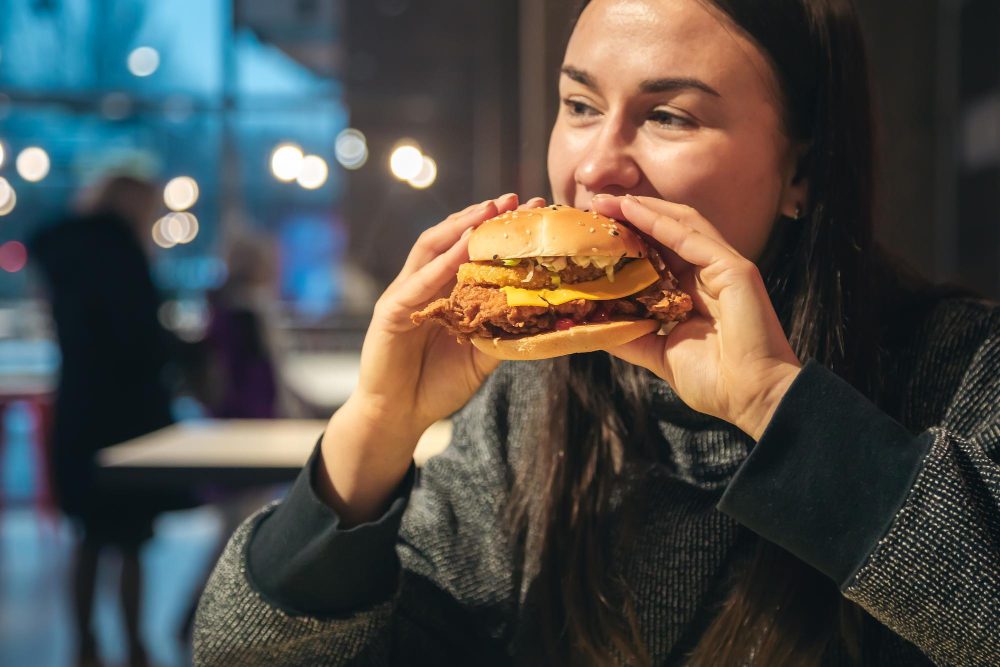 Žena si vychutnáva hamburger v reštaurácii.