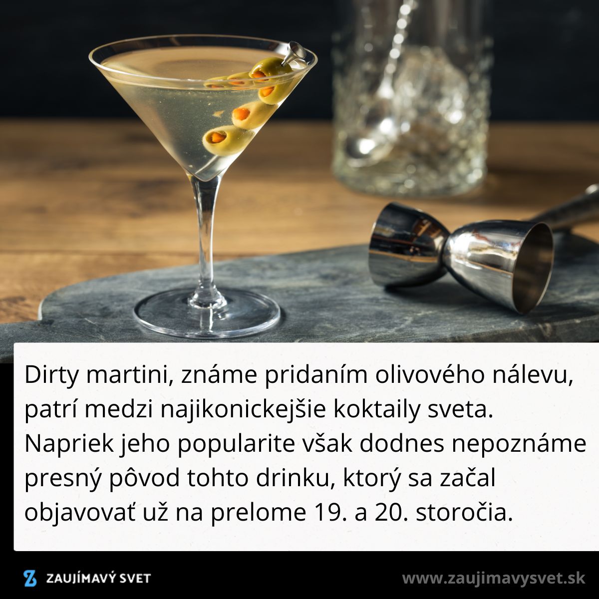 Koktail Dirty Martini s olivami na stole, vedľa barmanského náradia. Elegantný alkoholický nápoj.