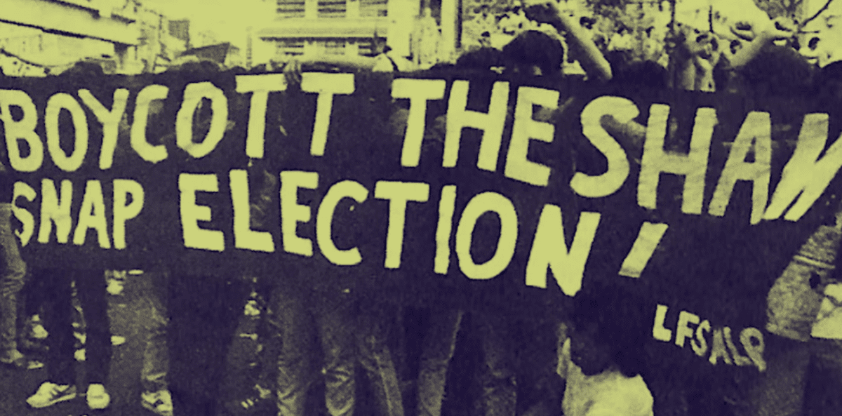Protestujúci s transparentom s nápisom: Boycott the sham snap election počas demonštrácie v mestskom prostredí.
