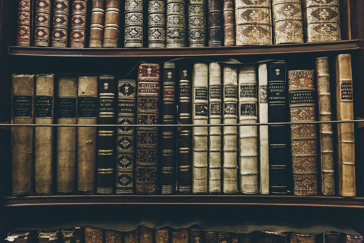 Stará knižnica s radom historických kníh viazaných v koži na drevenej poličke, symbolizujúca klasickú literatúru.