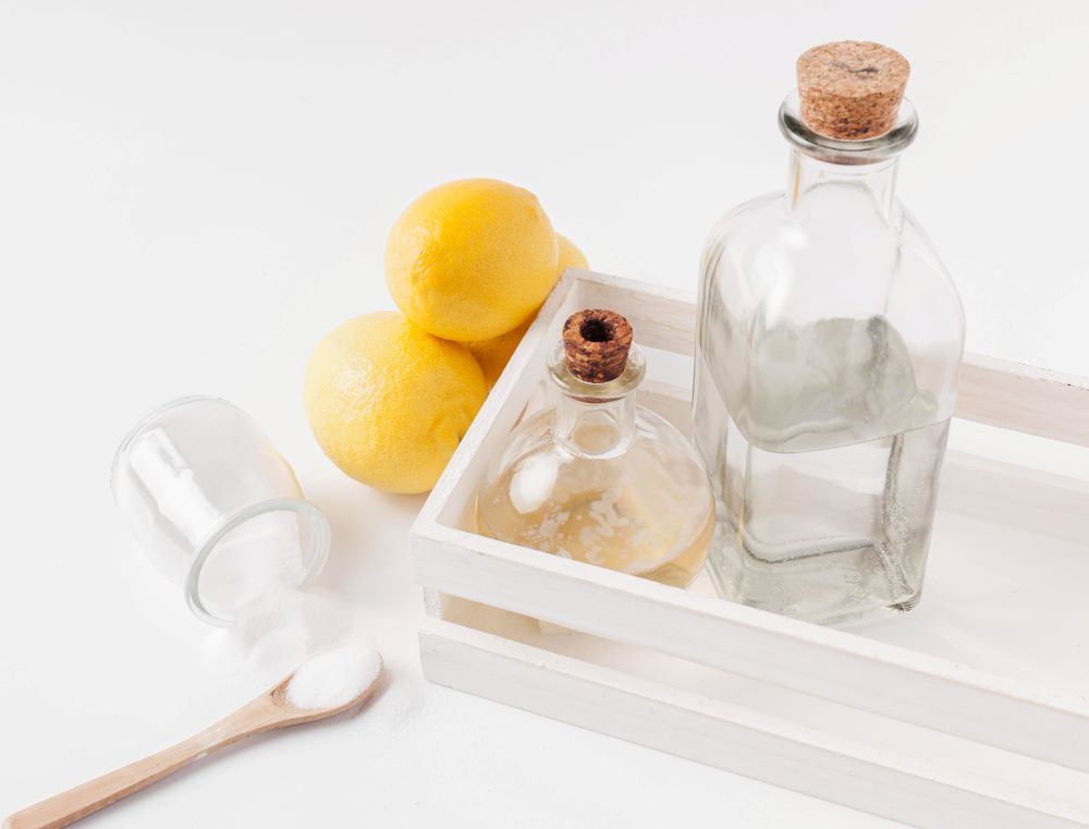 Citróny, sklenené fľaše a rozsypaný cukor na drevenom podnose, minimalistická kompozícia surovín.