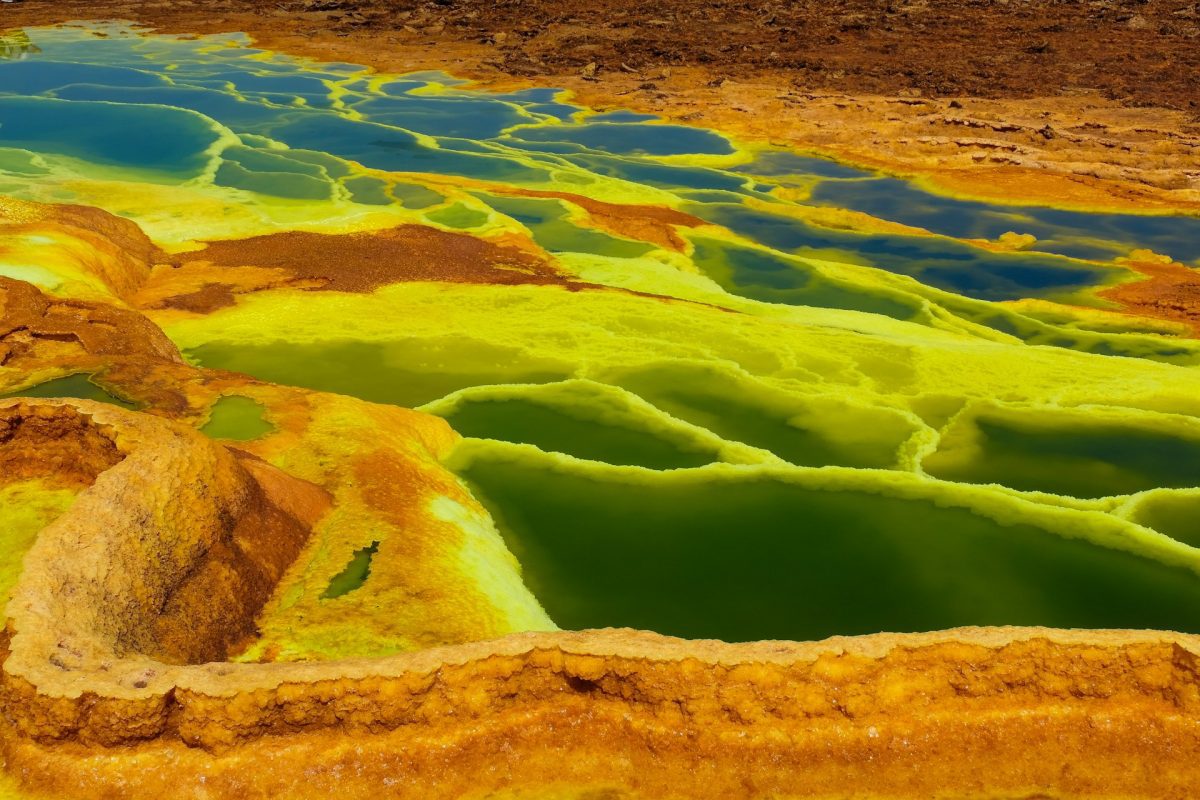 Farebný geotermálny prameň v Dallole, Etiópii s výraznými zeleno-žltými minerálnymi usadeninami.