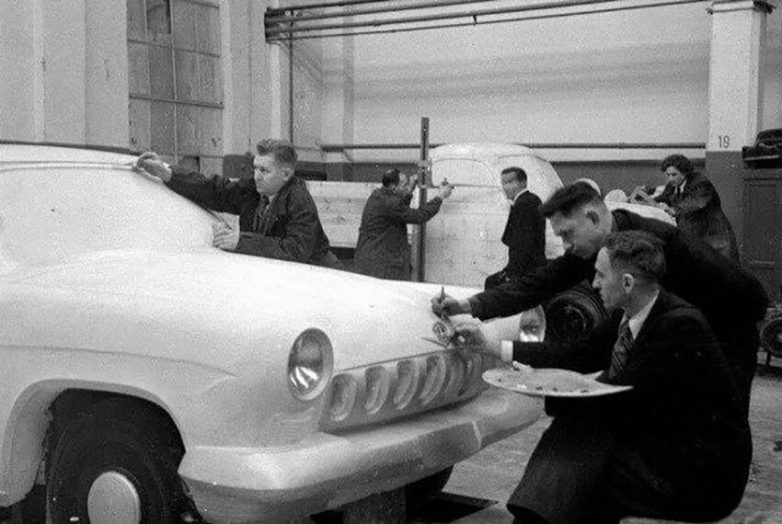 Dizajnéri pracujú na modeli auta v dielni, konštrukcia a kreatívne procesy v automobilovom priemysle.
