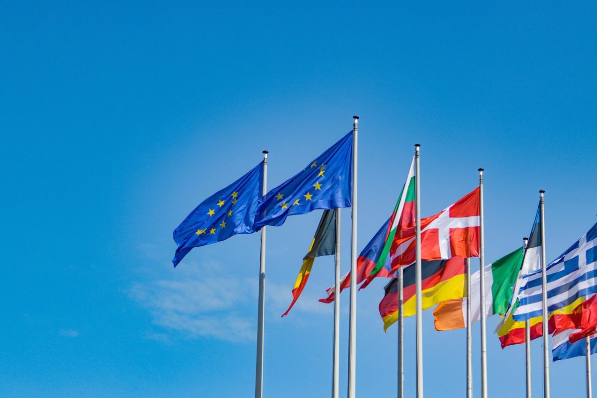 Zástavy Európskej únie a niektorých členských krajín vejúce na modrej oblohe.