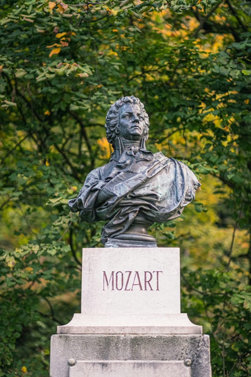 Busta Mozarta v záhrade, obklopená zelenými listami, zachytáva slávneho skladateľa v bronzovom prevedení.