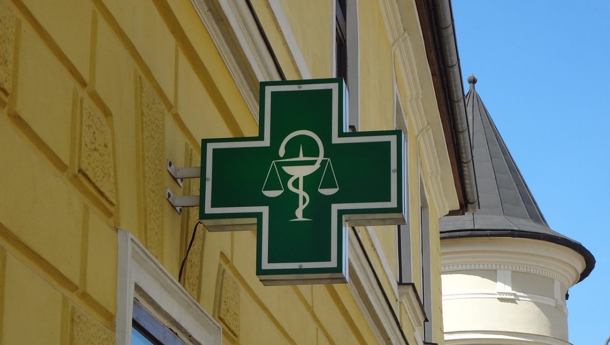 Zelený kríž s lekárskym symbolom na fasáde budovy signalizujúci lekáreň.