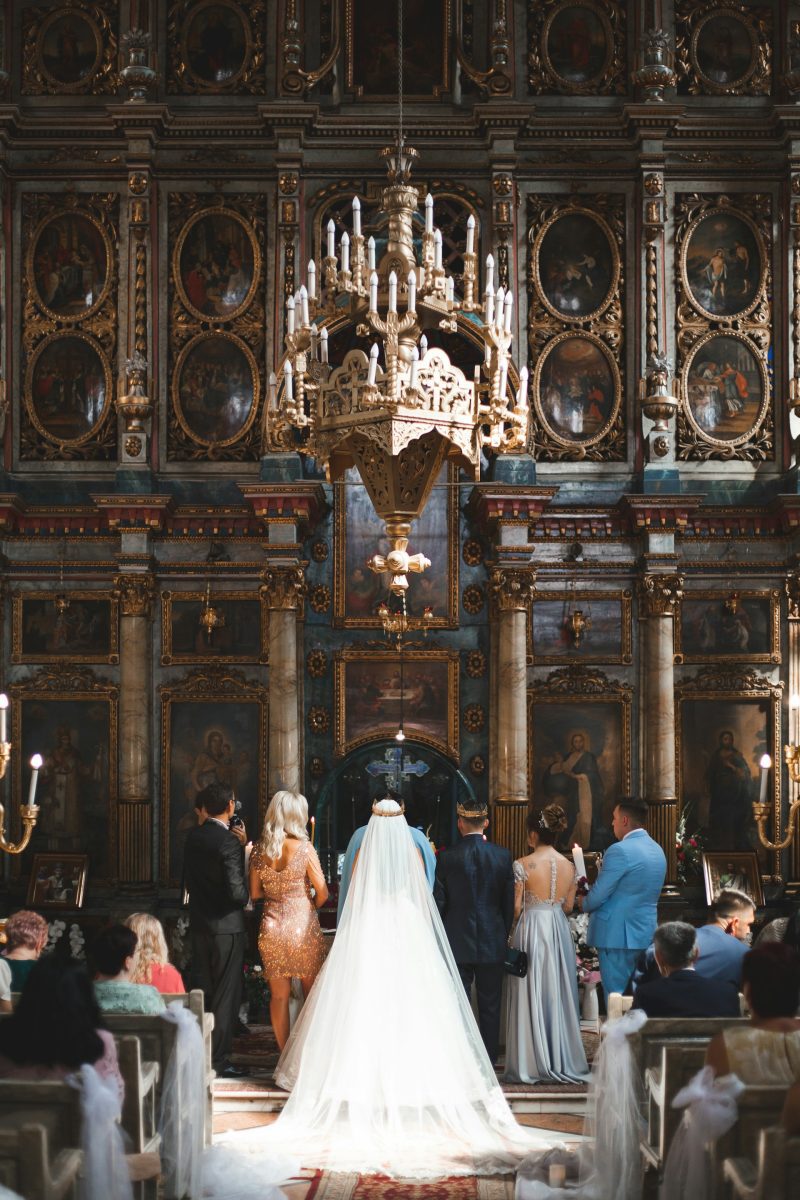 Svadba v historickom kostole s bohatou výzdobou, nevesta a hostia stoja pred oltárom.