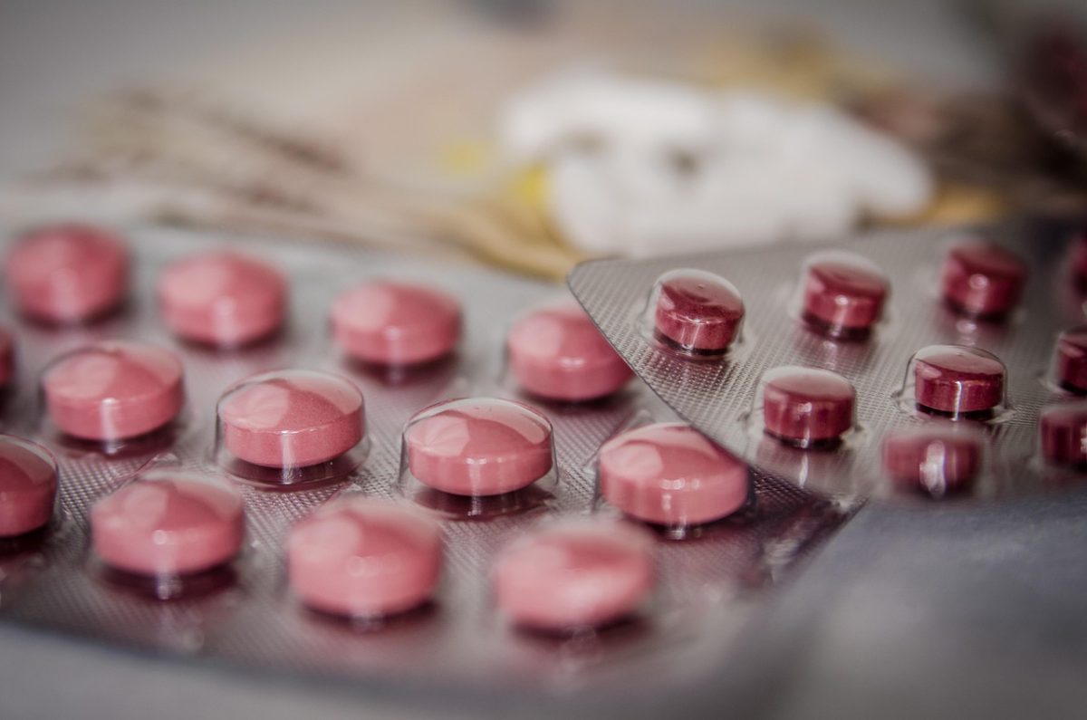 Ružové tabletky v blistrovom balení na stole, zamerané na farmaceutické produkty.