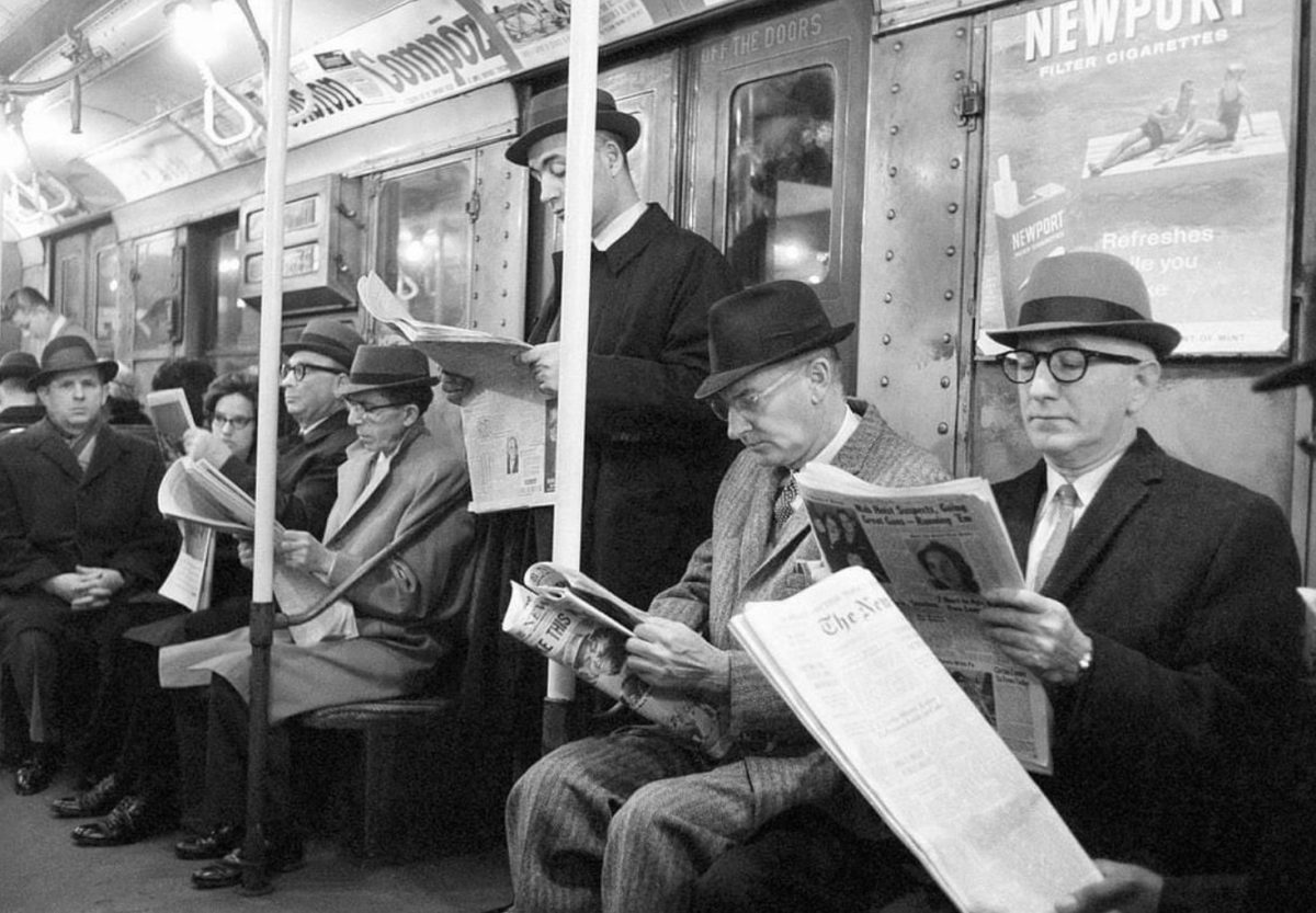 Cestujúci v starom metropolitnom vlaku čítajúci noviny, pričom nosia klobúky a obleky. Retro atmosféra mestskej dopravy.
