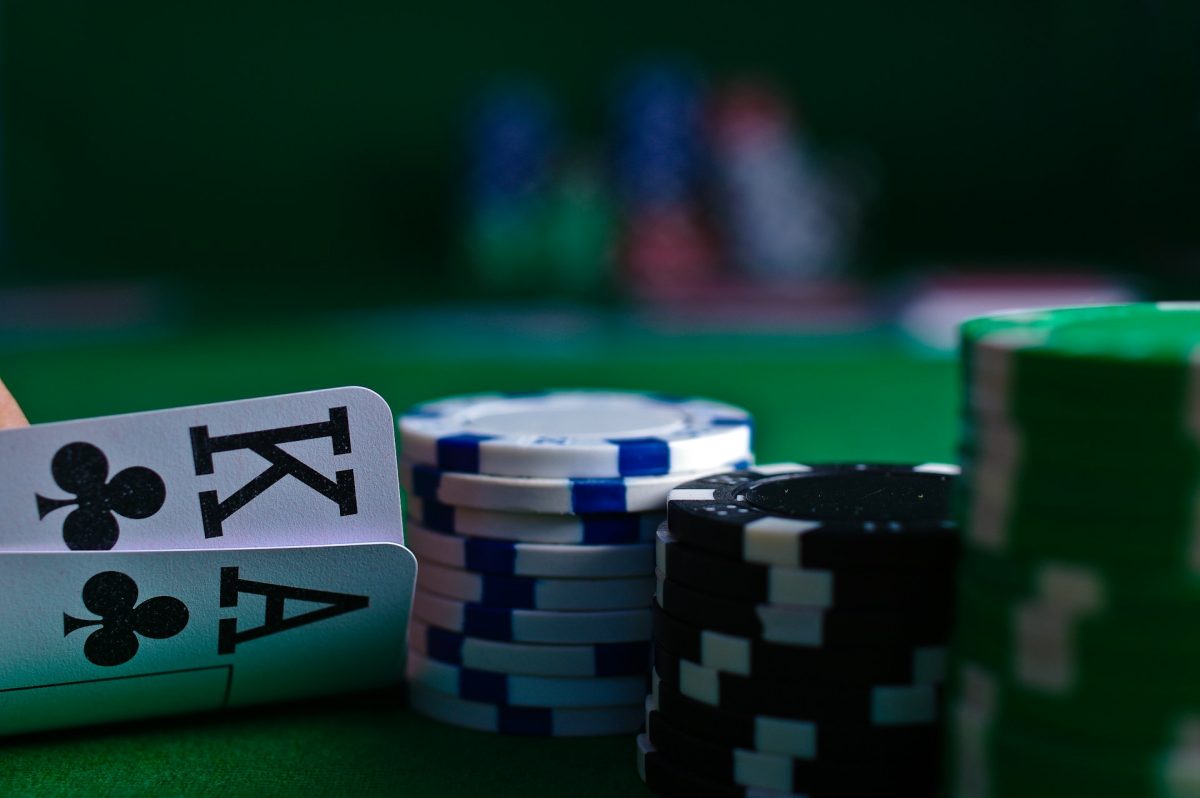 Pokerová hra s kartami a žetónmi na zelenej ploche, eso a kráľ palice.