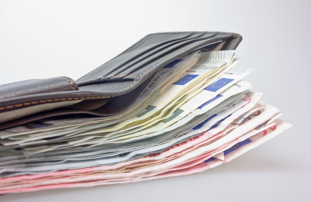 Kožená peňaženka plná eurobankoviek na bielom pozadí.