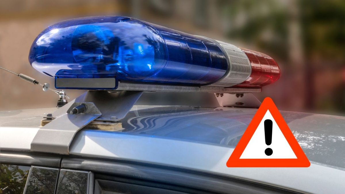 Policajné vozidlo so zapnutým svetelným majákom a výstražným symbolom na streche.
