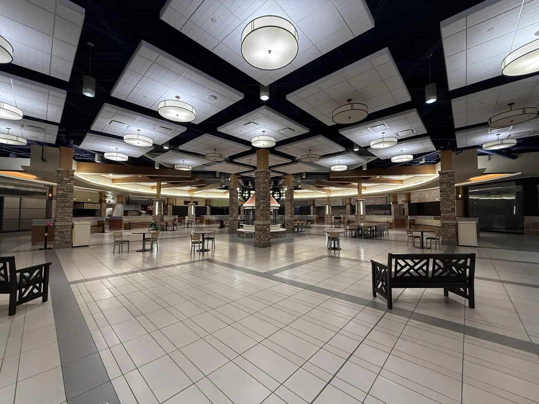 Prázdna moderná food court so stropným osvetlením a voľnými stolmi v obchodnom centre.