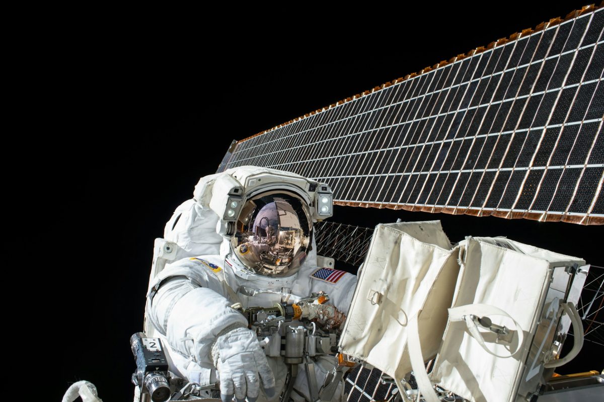 Astronaut pracujúci na údržbe solárnych panelov vo vesmíre, v pozadí nekonečný vesmír.